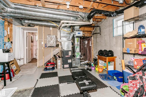 Exposed ceiling joists and ductwork, concrete walls, and a utility room featuring a furnace and water heater - 9760 64 Avenue, Edmonton, AB - Indoor Photo Showing Basement