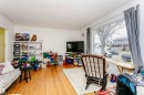 Spacious living area featuring expansive windows, wood-finish flooring, a textured ceiling, and an open layout - 9760 64 Avenue, Edmonton, AB  - Indoor 