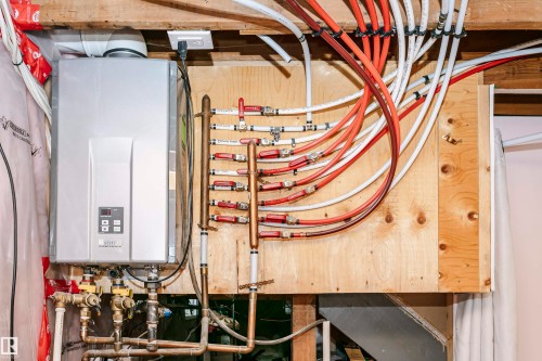 Tankless water heater installation with integrated PEX plumbing manifold on a plywood mounting board - 9760 64 Avenue, Edmonton, AB - Indoor Photo Showing Basement