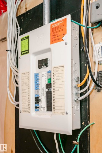 Electrical service panel with multiple circuit breakers and wiring connections - 9760 64 Avenue, Edmonton, AB - Indoor Photo Showing Basement