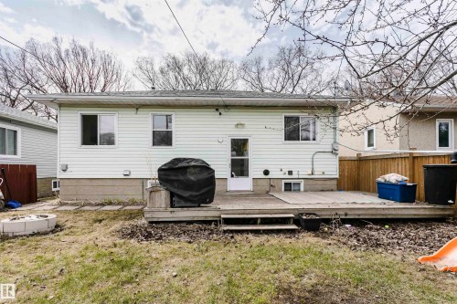 Rear exterior featuring white horizontal siding, a multi-level wood deck, a rear entry door, and multiple windows - 9760 64 Avenue, Edmonton, AB - Outdoor With Deck Patio Veranda With Exterior