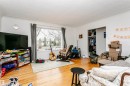 Spacious living area featuring wood-finish flooring, a large window with ample natural light, and a built-in closet with sliding doors - 9760 64 Avenue, Edmonton, AB  - Indoor 
