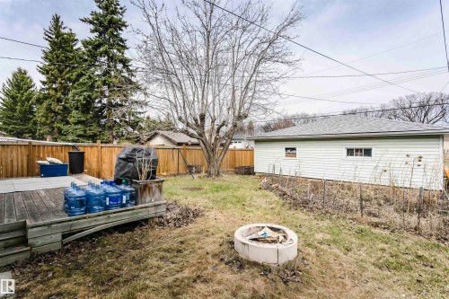 Spacious backyard featuring a wooden deck with steps, a concrete fire pit, and a mature tree - 9760 64 Avenue, Edmonton, AB - Outdoor