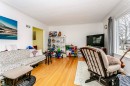 Bright living area featuring wood-finish flooring, white walls, and a large window with natural light - 9760 64 Avenue, Edmonton, AB  - Indoor Photo Showing Living Room 
