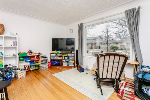 Hardwood flooring throughout a room with white walls and a large picture window - 9760 64 Avenue, Edmonton, AB - Indoor