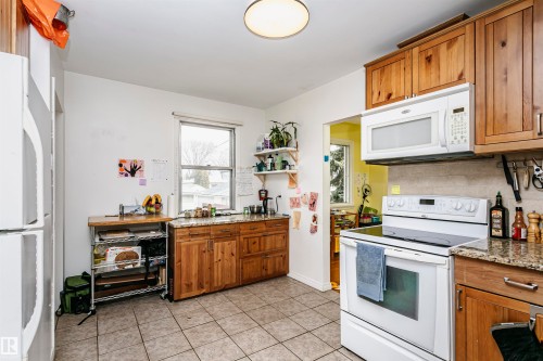 Kitchen featuring wood-finish cabinetry with granite-style countertops - 9760 64 Avenue, Edmonton, AB - Indoor Photo Showing Kitchen