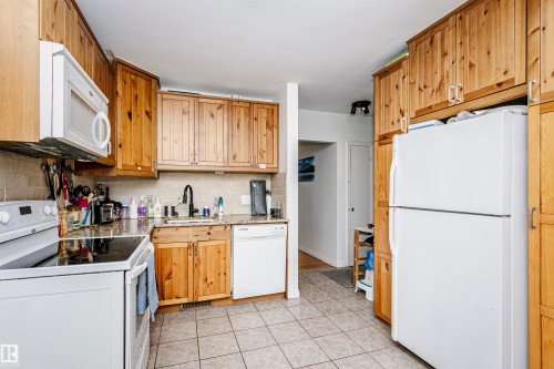 Kitchen featuring light wood cabinetry, stone-finish countertops, and a tile backsplash - 9760 64 Avenue, Edmonton, AB - Indoor Photo Showing Kitchen