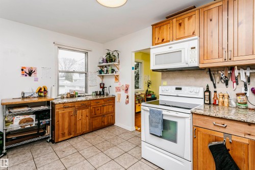 Kitchen featuring wood-finish cabinetry, stone countertops, and tile flooring - 9760 64 Avenue, Edmonton, AB - Indoor Photo Showing Kitchen