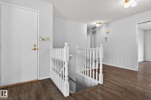 Hallway featuring wood-finish flooring and a white staircase with balusters - 46 903 109 Street, Edmonton, AB - Indoor Photo Showing Other Room