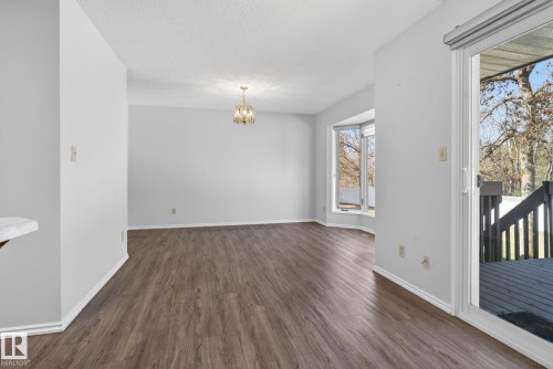 Spacious interior featuring wood-finish flooring, a contemporary chandelier, a bay window, and a sliding glass door opening to an exterior deck - 46 903 109 Street, Edmonton, AB - Indoor Photo Showing Other Room