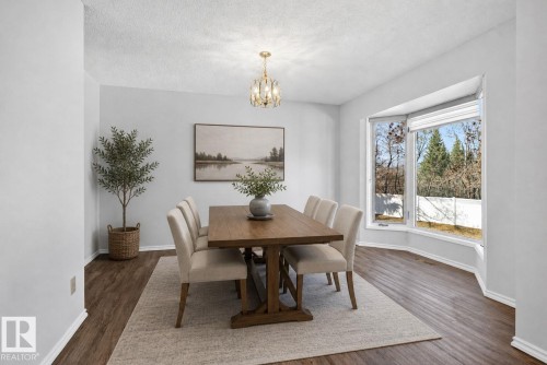 Formal dining area featuring wood-finish flooring and a contemporary chandelier - 46 903 109 Street, Edmonton, AB - Indoor Photo Showing Dining Room