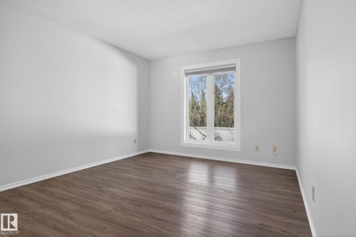 Bright room featuring a large window, wood-finish flooring, white baseboards, and neutral wall paint - 46 903 109 Street, Edmonton, AB - Indoor Photo Showing Other Room