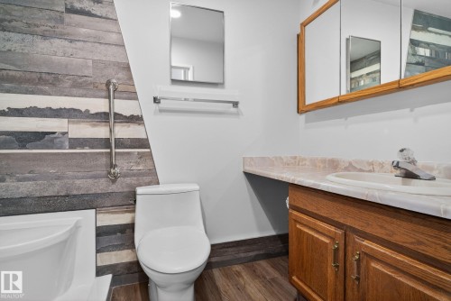 Bathroom featuring a wood-finish vanity with a built-in sink, a wall-mounted medicine cabinet, and a contemporary toilet - 46 903 109 Street, Edmonton, AB - Indoor Photo Showing Bathroom
