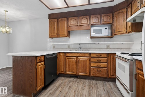 Kitchen featuring wood cabinetry, white countertops, white tile backsplash, and wood-finish flooring - 46 903 109 Street, Edmonton, AB - Indoor Photo Showing Kitchen With Double Sink