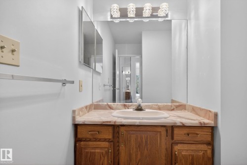 Bathroom vanity featuring a built-in sink, wood cabinetry, and a patterned countertop - 46 903 109 Street, Edmonton, AB - Indoor Photo Showing Bathroom
