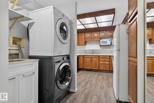 Dedicated laundry area with stackable appliances and a white vanity with integrated sink - 46 903 109 Street, Edmonton, AB - Indoor Photo Showing Laundry Room