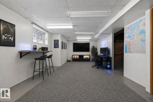 Finished lower level with textured gray carpeting, white walls, and a drop ceiling with fluorescent lighting - 46 903 109 Street, Edmonton, AB - Indoor Photo Showing Other Room