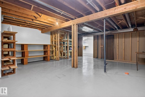 Unfinished basement featuring exposed wood joists, structural beams, and built-in shelving units - 46 903 109 Street, Edmonton, AB - Indoor Photo Showing Basement