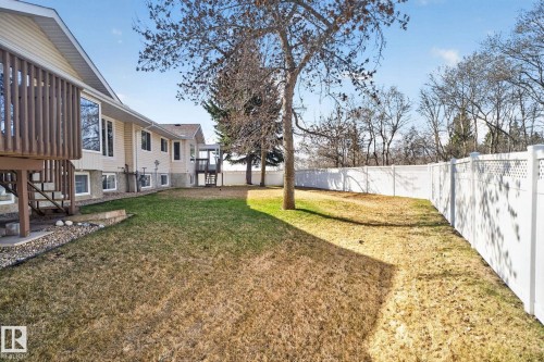 Expansive fenced backyard featuring a broad lawn, mature trees, and a multi-level deck with wood railings - 46 903 109 Street, Edmonton, AB - Outdoor