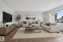 Spacious room featuring wood-finish flooring, light-colored walls, and a large window with white trim - 46 903 109 Street, Edmonton, AB  - Indoor Photo Showing Living Room 