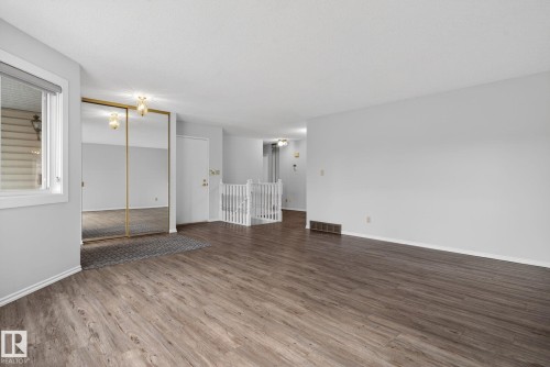 Spacious room featuring wood-finish flooring, light grey painted walls, and white baseboards - 46 903 109 Street, Edmonton, AB - Indoor Photo Showing Other Room