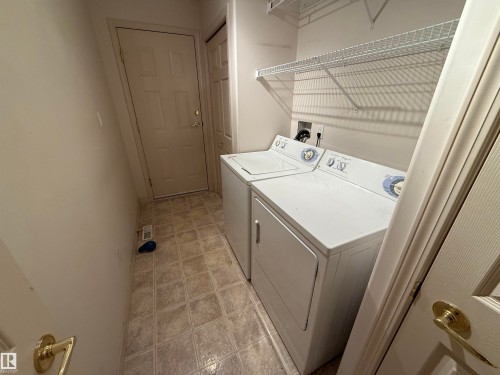 Utility space featuring square floor tiles, a built-in wire shelving unit, and multiple panel doors - 14 330 Galbraith Close, Edmonton, AB - Indoor Photo Showing Laundry Room