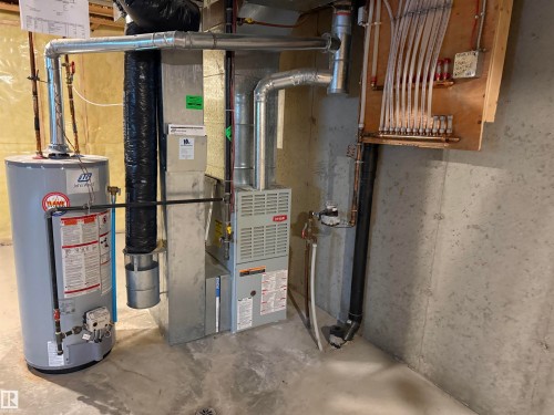 Utility area featuring a water heater, furnace, and a manifold system for radiant floor heating - 14 330 Galbraith Close, Edmonton, AB - Indoor Photo Showing Basement