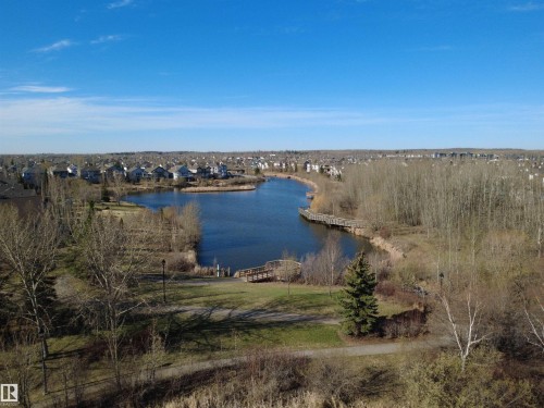 Expansive waterscape featuring a large body of water, a wooden boardwalk, shoreline vegetation, and surrounding residential areas - 14 330 Galbraith Close, Edmonton, AB - Outdoor With Body Of Water With View