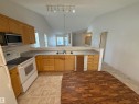 Kitchen featuring wood cabinetry, laminate countertops, and a white electric range - 14 330 Galbraith Close, Edmonton, AB  - Indoor Photo Showing Kitchen With Double Sink 