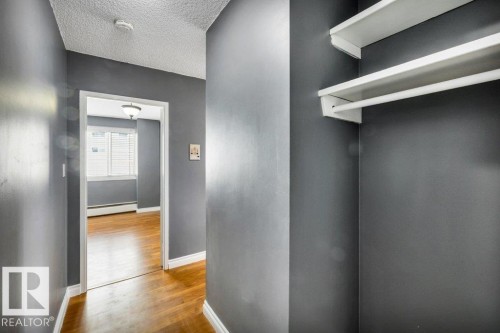 Hallway with wood-finish flooring and a built-in closet featuring white shelving and a hanging rod - 403 10021 116 Street, Edmonton, AB - Indoor Photo Showing Other Room