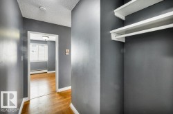 Hallway with wood-finish flooring and a built-in closet featuring white shelving and a hanging rod - 