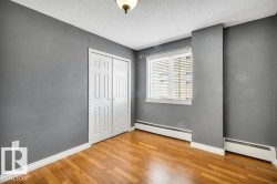 Room featuring wood-finish flooring, a double bi-fold closet, baseboard heating, a single window with blinds, and an overhead light fixture - 