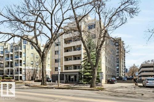 Multi-story apartment building featuring balconies, a prominent entrance, and surrounding mature trees - 403 10021 116 Street, Edmonton, AB - Outdoor With Facade