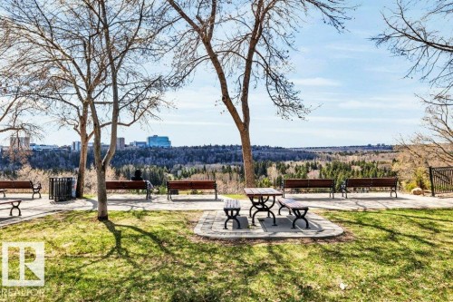 Expansive park setting featuring a paved pathway, established trees, and a distant city skyline - 403 10021 116 Street, Edmonton, AB - Outdoor With View
