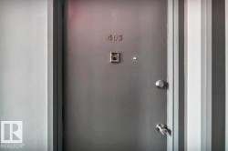 Solid gray entry door featuring a door knocker, peephole, and polished chrome hardware - 