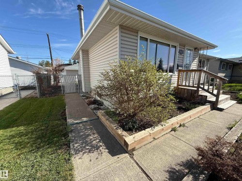 Exterior featuring light-toned vinyl siding, a prominent metal chimney, and a concrete walkway - 16112 87 Avenue, Edmonton, AB - Outdoor