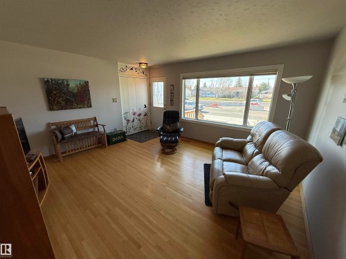 Hardwood flooring throughout a bright living space featuring a large picture window, a front entry door with decorative glass, and a coat closet - 16112 87 Avenue, Edmonton, AB - Indoor Photo Showing Living Room