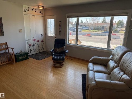 Living area featuring wood-finish flooring, a front entry door with decorative glass, and a large multi-pane window - 16112 87 Avenue, Edmonton, AB - Indoor