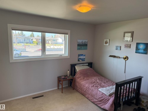 Bedroom featuring a large horizontal window, light neutral wall paint, and a ceiling-mounted light fixture - 16112 87 Avenue, Edmonton, AB - Indoor Photo Showing Bedroom