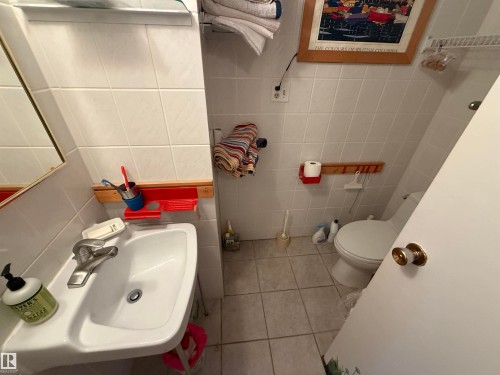 Compact bathroom featuring a white porcelain sink with a chrome faucet, white tile flooring, and white tiled walls - 16112 87 Avenue, Edmonton, AB - Indoor Photo Showing Bathroom