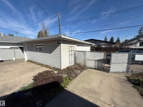 Detached garage with horizontal siding and a single window, featuring a concrete driveway and chain-link fencing - 16112 87 Avenue, Edmonton, AB - Outdoor With Exterior