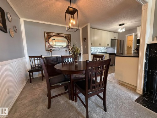 Dining area featuring wainscoting and a contemporary pendant light fixture - 5 2204 118 Street, Edmonton, AB - Indoor Photo Showing Dining Room