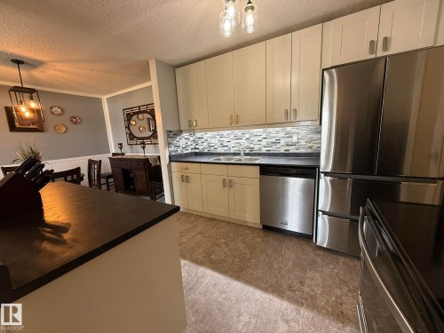 Kitchen featuring white cabinetry, dark countertops, and stainless steel appliances - 5 2204 118 Street, Edmonton, AB - Indoor Photo Showing Kitchen