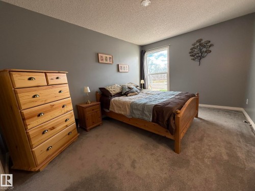 Bedroom featuring neutral carpeting, a window with outdoor scenery, and ceiling with a textured finish - 5 2204 118 Street, Edmonton, AB - Indoor Photo Showing Bedroom