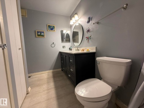 Vanity featuring a white countertop, oval mirror, and three-light fixture - 5 2204 118 Street, Edmonton, AB - Indoor Photo Showing Bathroom