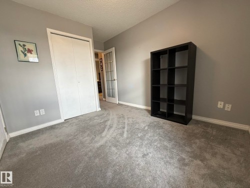 Carpeted room featuring light gray walls, white baseboards, and a white bi-fold closet door - 5 2204 118 Street, Edmonton, AB - Indoor Photo Showing Other Room