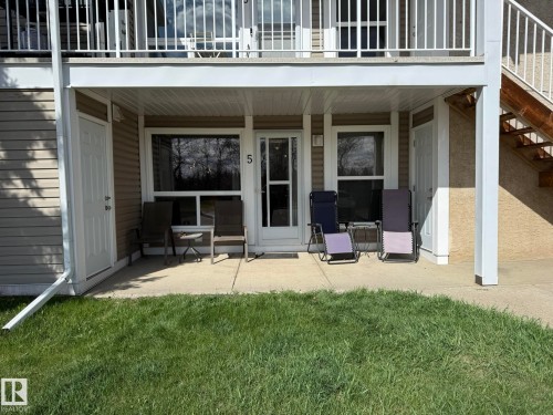 Ground-level patio featuring a concrete surface, tan siding, and a white overhead balcony - 5 2204 118 Street, Edmonton, AB - Outdoor