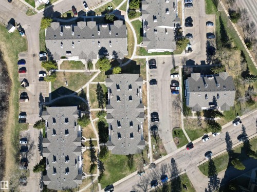 Aerial perspective of a multi-building residential community featuring pitched roofs, common green spaces, paved parking areas, and sidewalks - 5 2204 118 Street, Edmonton, AB - 