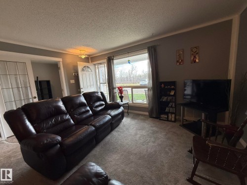 Living room featuring carpet flooring, a large front window, a white paneled front door, and a light fixture - 5 2204 118 Street, Edmonton, AB - Indoor Photo Showing Living Room