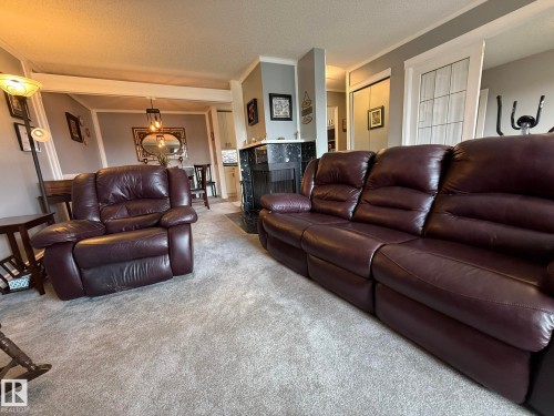 Spacious living area featuring light gray carpeting and a dark-toned fireplace with a black surround - 5 2204 118 Street, Edmonton, AB - Indoor Photo Showing Living Room